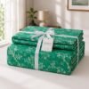 Neatly folded green floral cotton bedspread set tied with a white ribbon and product tag