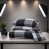 Front view of a double bed made with a grey and black large plaid buffalo check bedspread and matching pillows